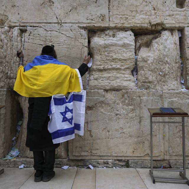 Un juif ultra-orthodoxe enveloppé dans des drapeaux nationaux ukrainien et israélien prie au Mur occidental, le site le plus sacré où les juifs peuvent prier dans la vieille ville de Jérusalem, le vendredi 4 mars 2022. [Keystone - AP Photo/Mahmoud Illean]