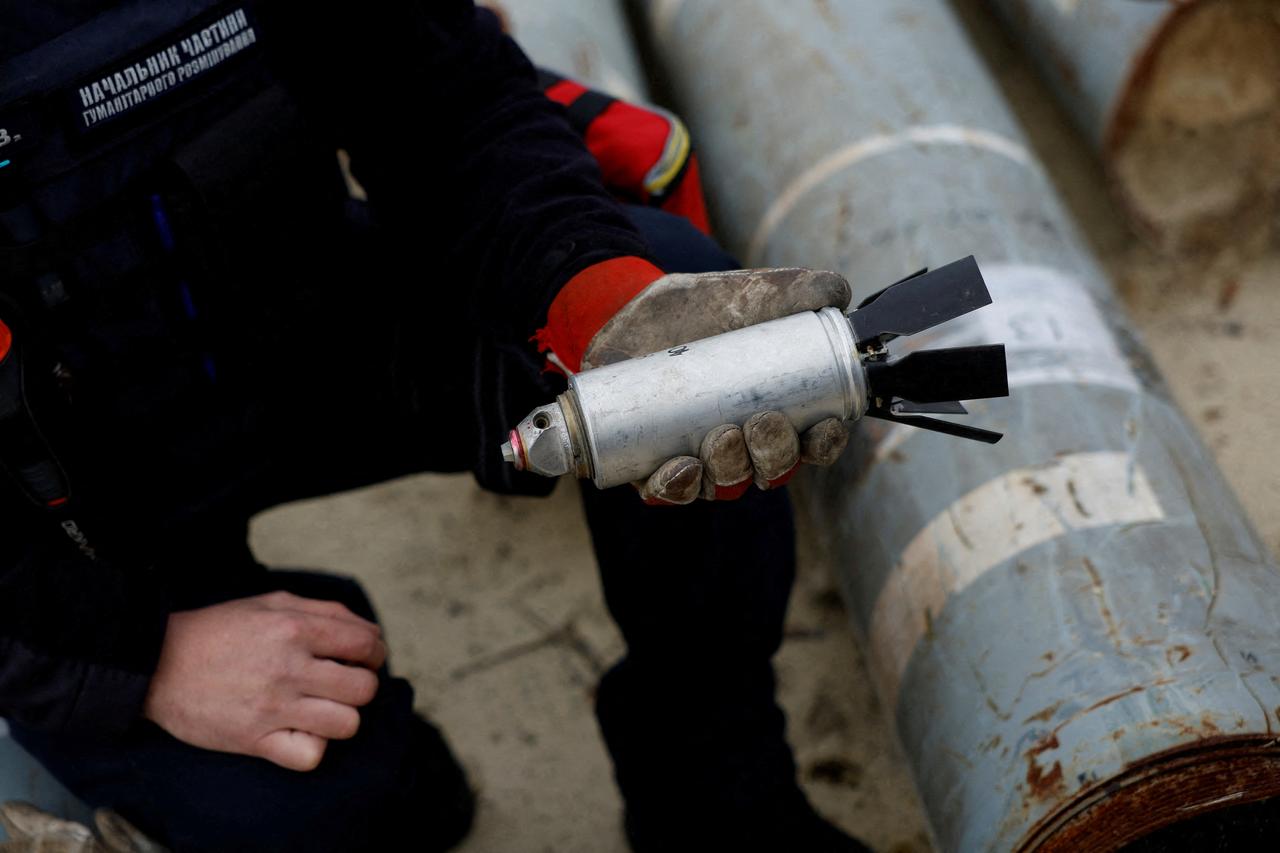 Un militaire ukrainien tient une sous-munition qui n'a pas explosé à l'impact d'un missile russe, le 21 octobre 2022. [Reuters - Clodagh Kilcoyne]