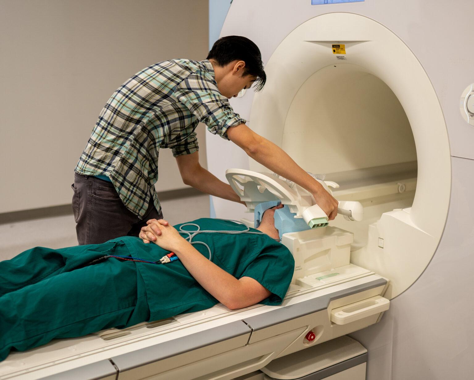 Jerry Tang se prépare à collecter des données sur l'activité cérébrale au centre d'imagerie biomédicale de l'Université du Texas à Austin. Le décodeur sémantique a été entraîné pendant des dizaines d'heures sur de données d'activité cérébrale de personnes participantes, collectées dans un scanner IRMf. [The University of Texas at Austin - Nolan Zunk]