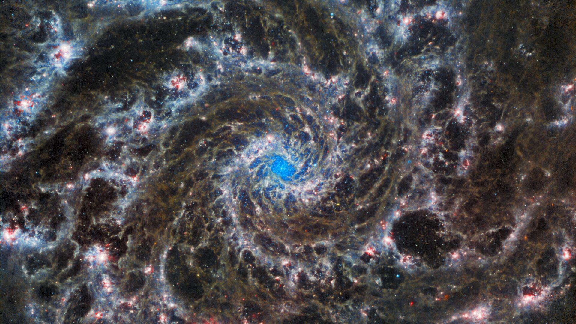 Le cœur de la galaxie M74, la "galaxie fantôme". JWST révèle de délicats filaments de gaz et de poussière dans les bras spiraux qui s'enroulent vers l'extérieur à partir du centre. L'absence de gaz dans la région nucléaire permet de voir l'amas d'étoiles au centre de la galaxie. Observation avec l'instrument en infrarouge moyen (MIRI) de James Webb. [ESA/Webb, NASA & CSA - J. Lee and the PHANGS-JWST Team]