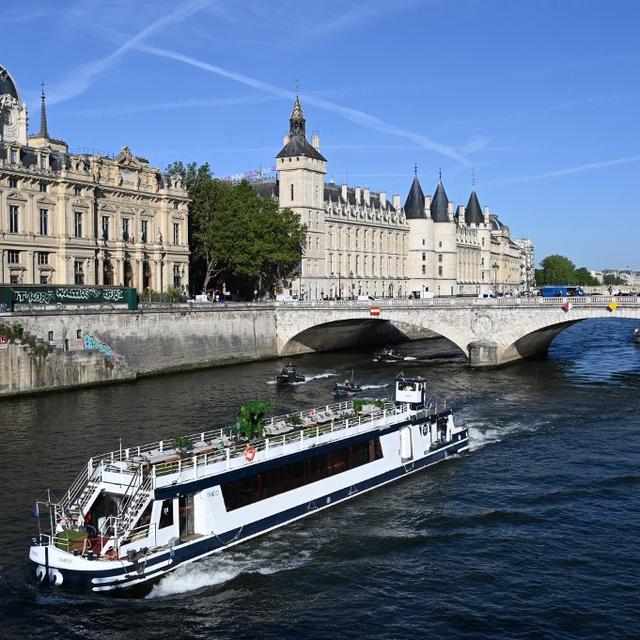 Un bateau péniche passe devant le Quai de l'Horloge lors d'un défilé sur la Seine à Paris le 17 juillet 2023, pour tester de "manœuvres" avant les JO 2024. [AFP]