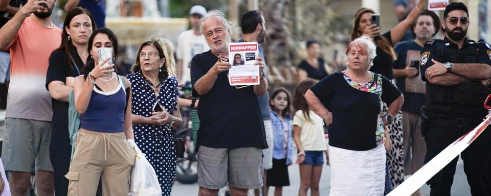 Des Israéliens regardent le cortège du président Joe Biden se diriger vers l'aéroport après sa rencontre avec le Premier ministre israélien Benjamin Netanyahu, le mercredi 18 octobre 2023, à Tel Aviv. [Keystone]