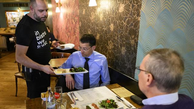 Un serveur apportant deux plats dans un restaurant à Lausanne. [Keystone - Laurent Gillieron]