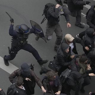 Un policier anti-émeute chasse des manifestants à l'aide d'une matraque à Paris, le 23 mars 2023. [Keystone - AP Photo/Christophe Ena]