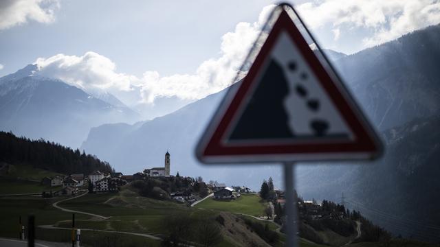 Vue du village et d'un panneau avertissant des chutes de pierres, prise le mardi 4 avril 2023 à Brienz-Brinzauls. [Keystone - Gian Ehrenzeller]