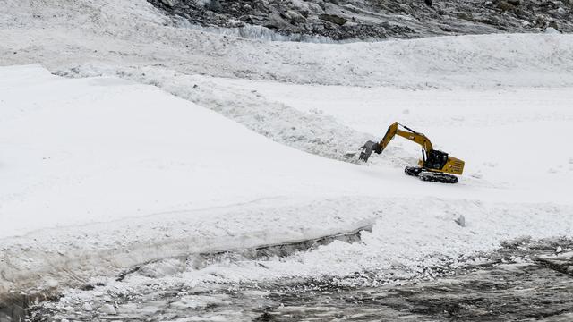 Une pelleteuse préparant les pistes de la Coupe du monde de ski à Zermatt-Cervinia. [Keystone - Jean-Christophe Bott]