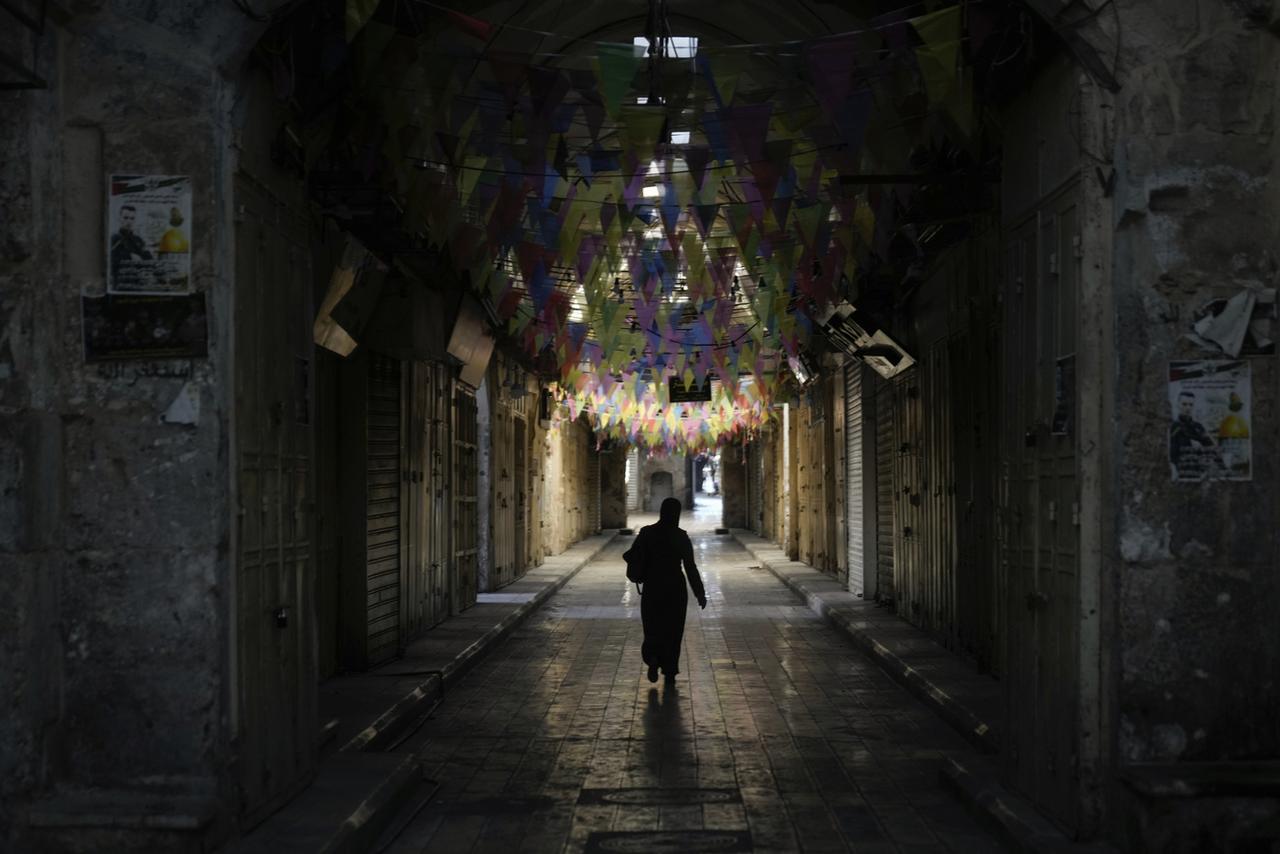 Lundi 11 décembre: une Palestinienne marche dans une rue déserte de Naplouse, en Ciosjordanie, où de nombreux commerces sont restés fermés durant le jour de grève pour exiger un cesser-le-feu à Gaza. [AP/Keystone - Majdi Mohammed]