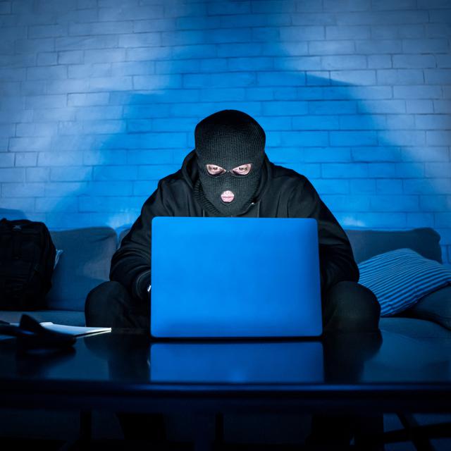 Homme masqué derrière un ordinateur. [Depositphotos - Milkos]