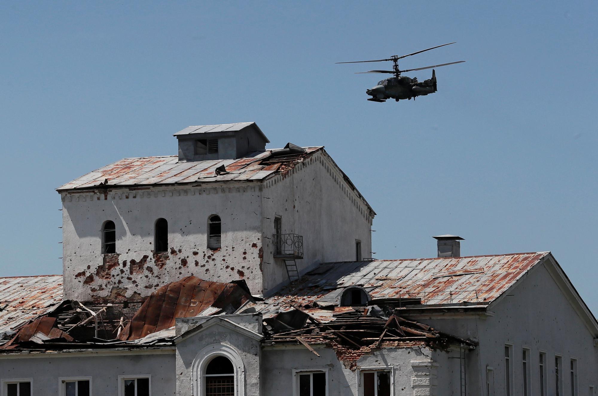 Un hélicoptère d'attaque russe Ka-52  vole près d'un bâtiment fortement endommagé dans la ville de Popasna, dans la région de Lougansk. [reuters - Alexander Ermochenko]
