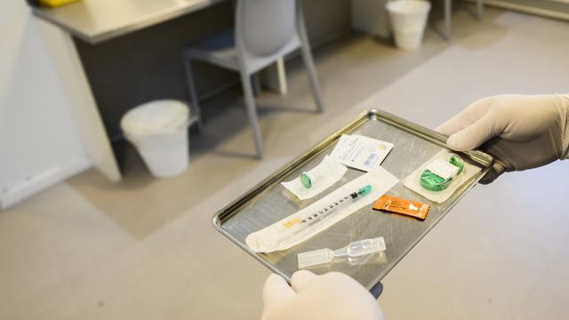 Une personne prépare des ustensiles pour la consommation de drogues dans un espace de consommation sécurisé à Lausanne. [Keystone - Jean-Christophe Bott]