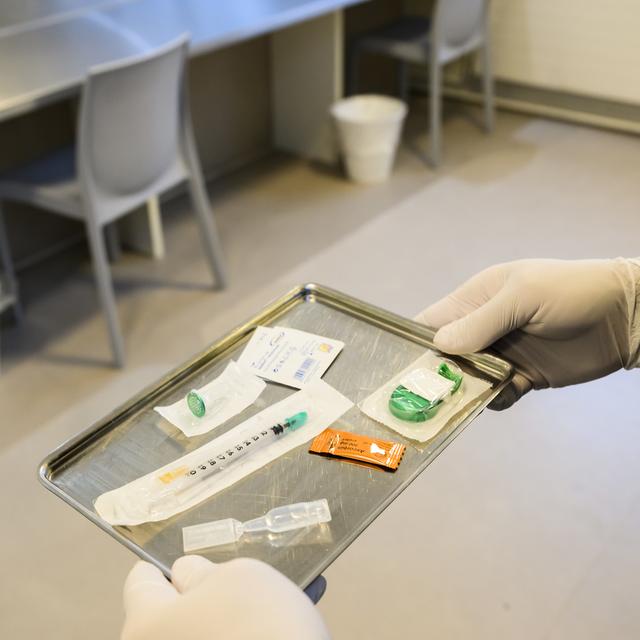 Une personne prépare des ustensiles pour la consommation de drogues dans un espace de consommation sécurisé à Lausanne. [Keystone - Jean-Christophe Bott]