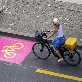 Une cycliste sur une piste cyclable à Genève [Keystone - Martial Trezzini]