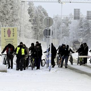Des garde-frontières finlandais escortent des migrants au Nord de la Finlande. [Keystone - Jussi Nukari/Lehtikuva via AP]