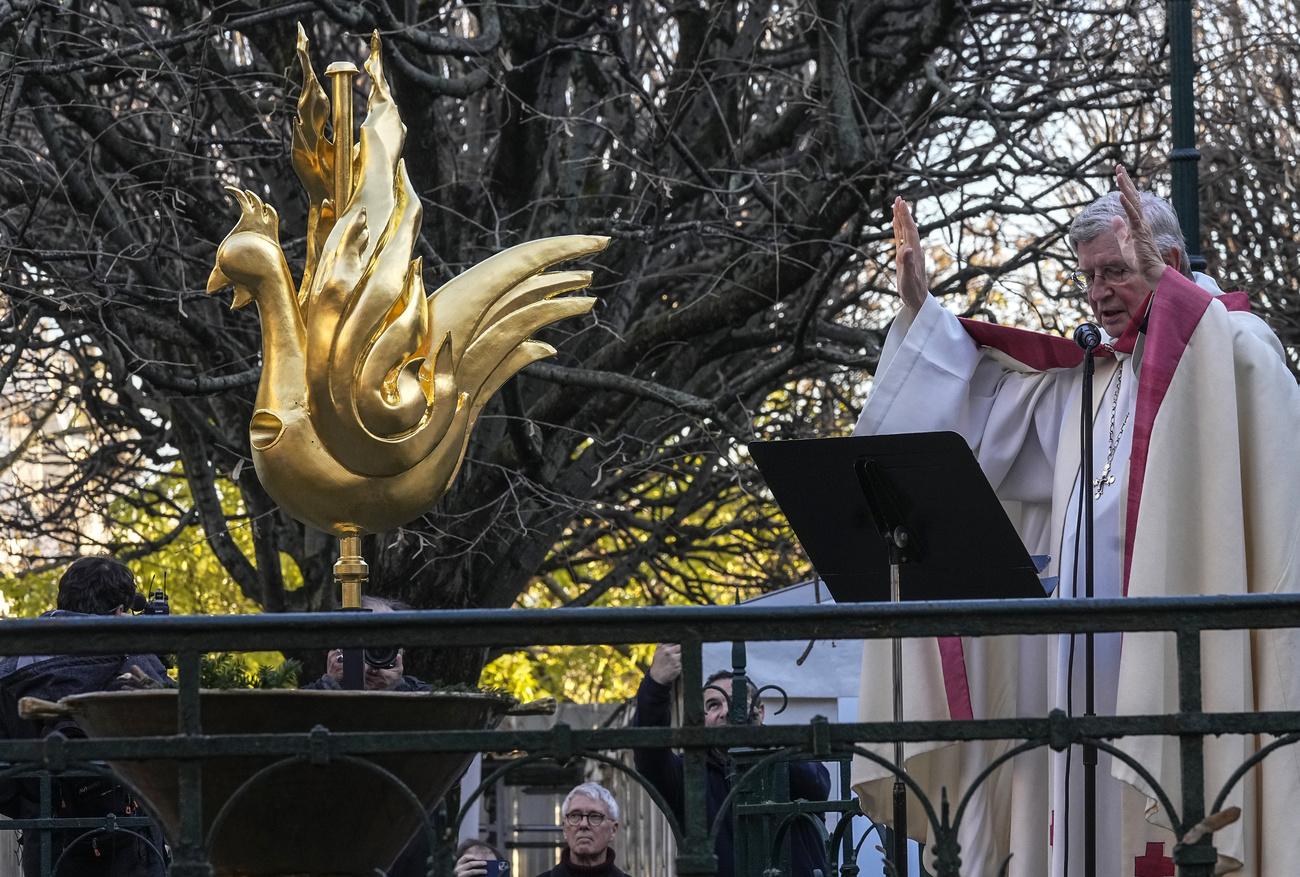 L'archevêque de Paris, Monseigneur Laurent Ulrich, bénit le fier gallinacé, avant qu'il ne soit installé au sommet de la flèche de Notre-Dame. [Keystone - Michel Euler/AP Photo]