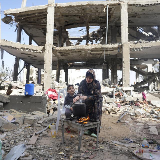 Dimanche 26 novembre: une femme prépare à manger devant sa maison familiale détruite à Khan Younis, dans la bande de Gaza, au 3e jour du cessez-le-feu temporaire entre Israël et le Hamas. [AP/Keystone - Adel Hana]