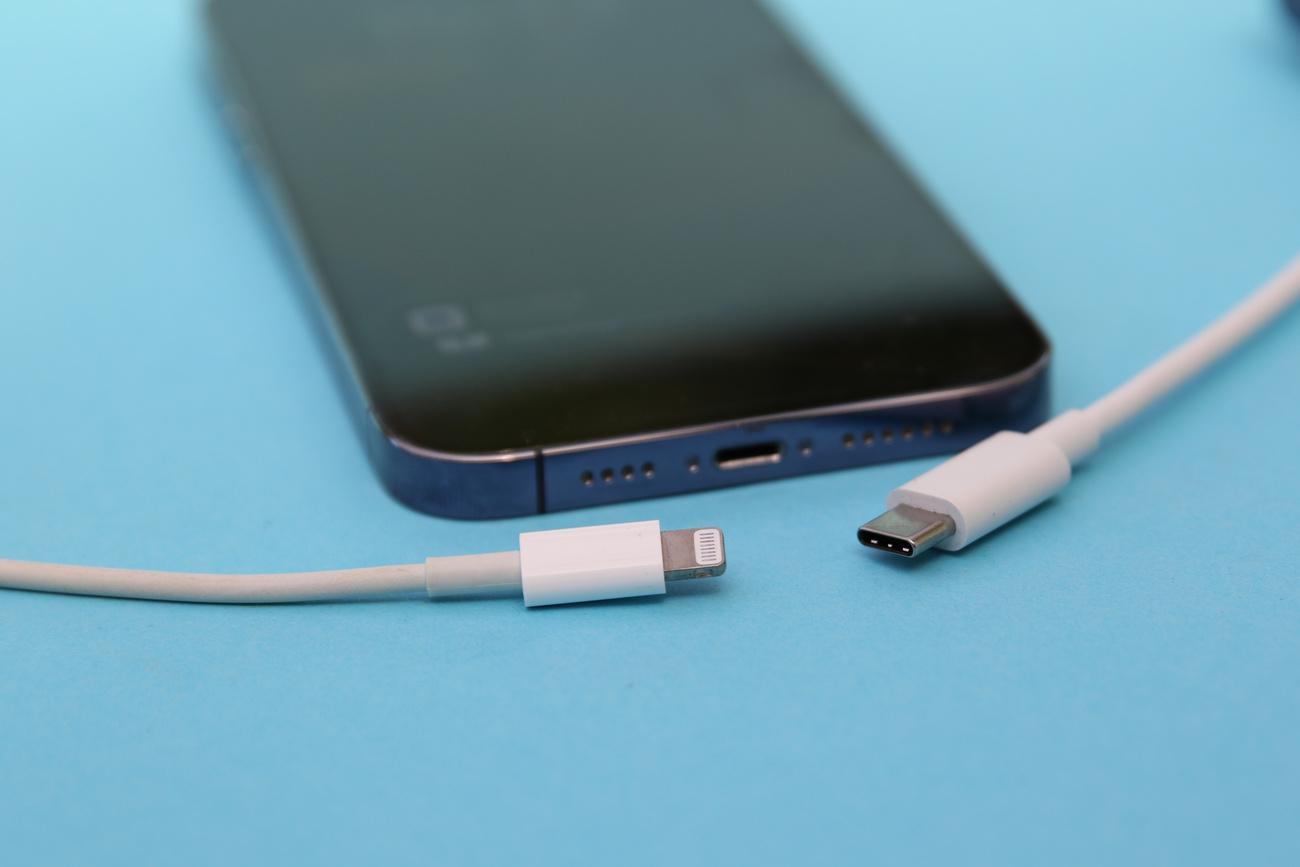 Un iPhone avec un câble "Lightning" d'Apple (à gauche) et un câble USB-C (à droite). [KEYSTONE - CHRISTOPH DERNBACH]