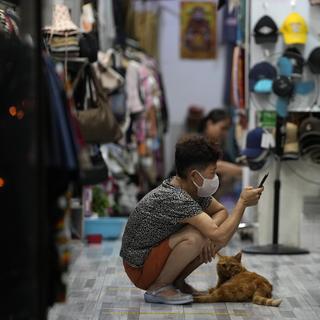 Une femme attend des clients en compagnie de son chat dans un magasin de Beijing, Chine. [Keystone/AP Photo - Ng Han Guan]