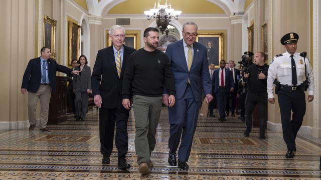 Le président ukrainien Volodymyr Zelenskyy est escorté par le chef de la minorité du Sénat Mitch McConnell, R-Ky et le chef de la majorité du Sénat Chuck Schumer, D-N.Y., le 12 décembre 2023. [KEYSTONE - J. SCOTT APPLEWHITE]