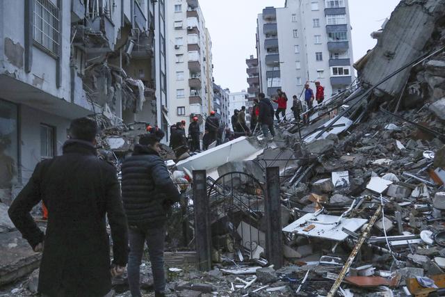 Des secouristes à pied d'oeuvre sur les décombres d'un immeuble effondré à Adana, en Turquie. [Keystone - IHA agency via AP]