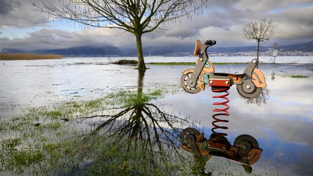 Une place de jeux inondée  à Cudrefin (VD) sur la rive nord-est du lac de Neuchâtel, photographiée le jeudi 14 décembre 2023. [Keystone - Jean-Christophe Bott]
