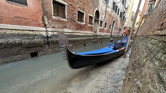 Une gondole est amarrée sur un canal asséché pendant une marée basse à Venise le 20 février 2023. [Keystone - AP Photo/Luigi Costantini]