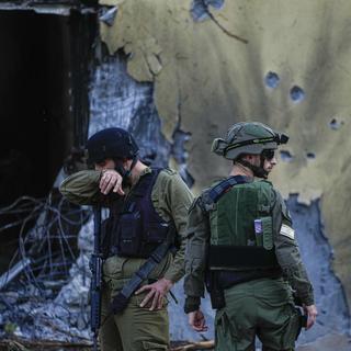 Des soldats israéliens près d'un kibboutz détruit. [Keystone - Ariel Schalit]