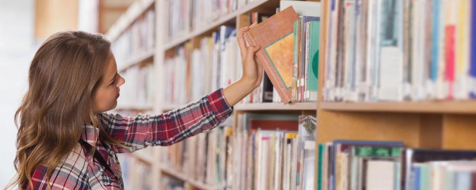 Une femme regarde les livres dans une bibliothèque. (image d'illustration) [Depositphotos - Wavebreakmedia]