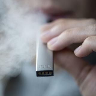 Une personne fume une cigarette électronique Juul. [Keystone - Ennio Leanza]