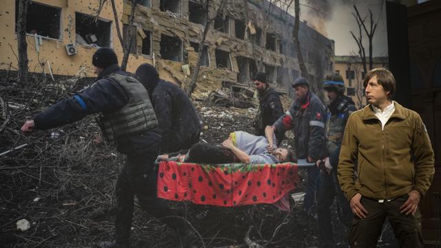 Vainqueur du World Press Photo, Evgeniy Maloletka pose à côté de son cliché pris à Marioupol, en Ukraine. [Keystone - AP Photo/Peter Dejong]