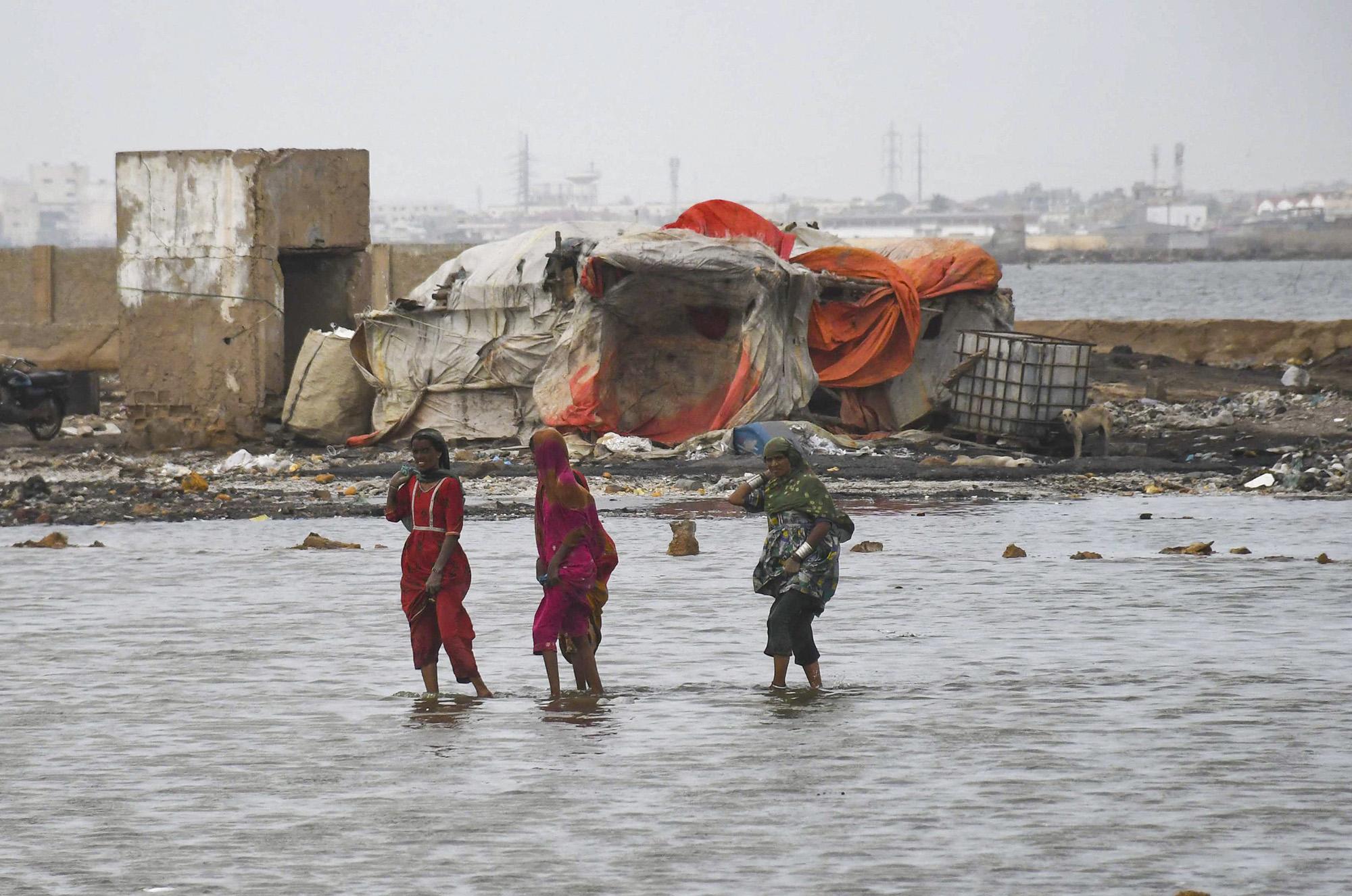 Les victimes des inondations pakistanaises traversent l'eau en raison du cyclone Biparjoy qui s'approche de la zone côtière de Karachi, au Pakistan. [AFP - Sabir Mazhar]