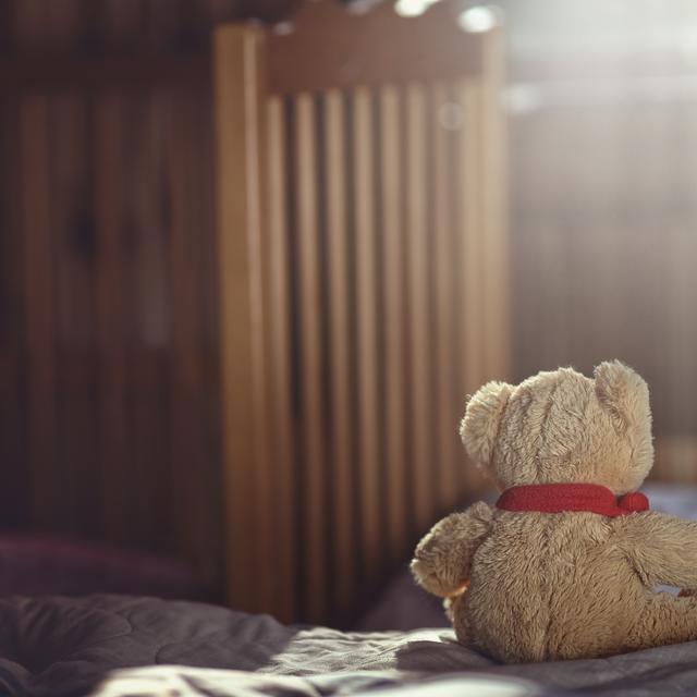 Un ourson en peluche dans une chambre d'enfant vide. [Depositphotos - ambrozinio]