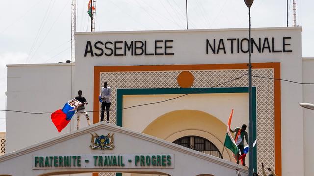 Des manifestants arborant des drapeaux du Niger et de la Russie escaladent la porte de l'Assemblée nationale en soutien au coup d'État militaire au Niger (image d'illustration). [Keystone/EPA - Issifou Djibo]