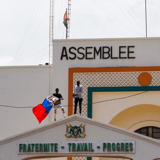 Des manifestants arborant des drapeaux du Niger et de la Russie escaladent la porte de l'Assemblée nationale en soutien au coup d'État militaire au Niger (image d'illustration). [Keystone/EPA - Issifou Djibo]