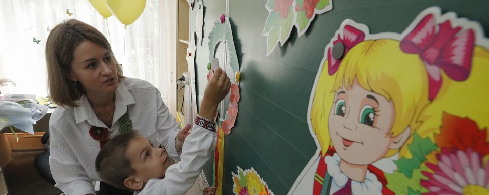 Les enfants ukrainiens ont repris le chemin des salles d'école le 1er septembre 2023. [Keystone/EPA - Sergey Dolzhenko]