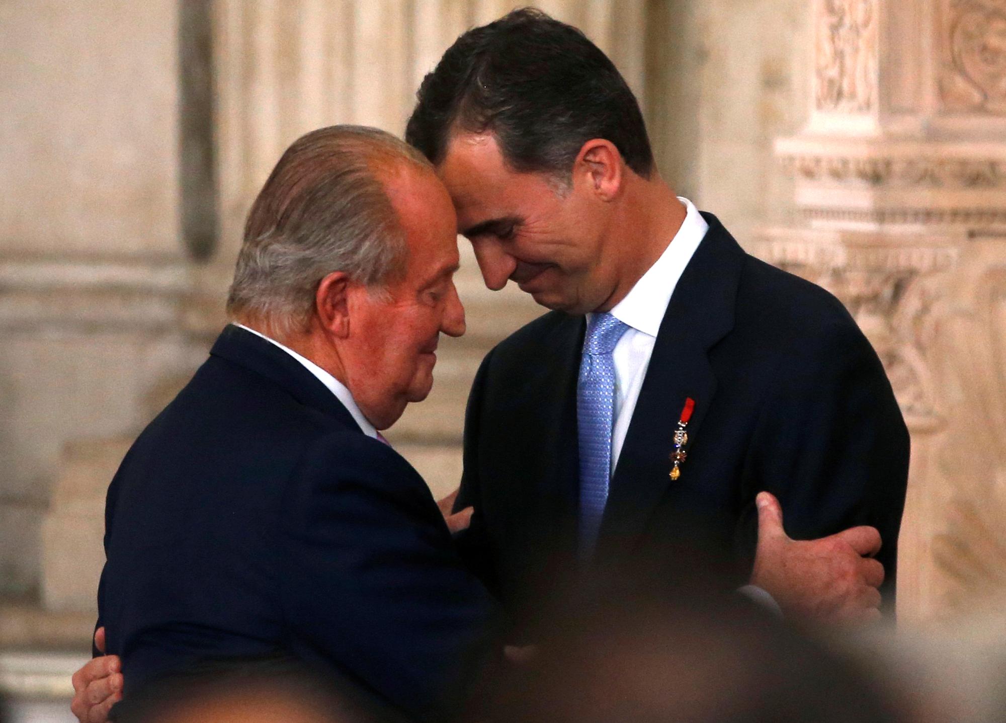 L'accolade du roi d'Espagne Juan Carlos et du prince Felipe avant la cérémonie de l'acte d'abdication, au Palais royal de Madrid, le 18 juin 2014. [REUTERS - Juan Medina]