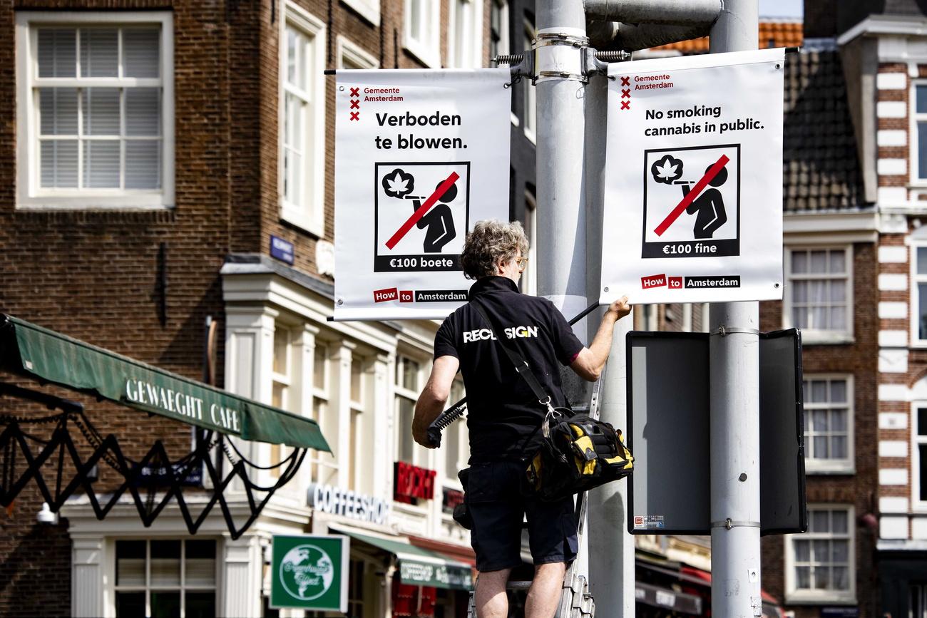 Amsterdam fait la chasse à la fumette dans les rues. Sur cette photo prise le 23 mai, un employé municipal accroche les pancartes annonçant l'amende guettant les fumeurs de cannabis. [Keystone - Ramon van Flymen/EPA]