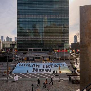 Des militants de Greenpeace déploient une banderole devant le siège des Nations unies pendant les négociations en cours à l'ONU sur un traité de protection de la haute mer, à New York, le 27 février 2023. [AFP - Ed Jones]