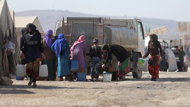 Des réfugiés syriens remplissent un réservoir d'eau au camp de Kalbeet, dans le nord d'Idlib, le 29 octobre 2022. [Keystone - Yahya Nemah]