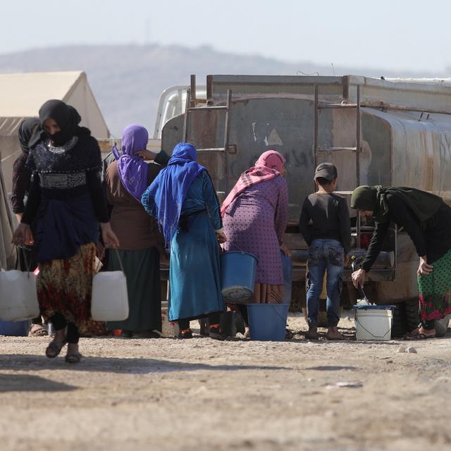 Des réfugiés syriens remplissent un réservoir d'eau au camp de Kalbeet, dans le nord d'Idlib, le 29 octobre 2022. [Keystone - Yahya Nemah]