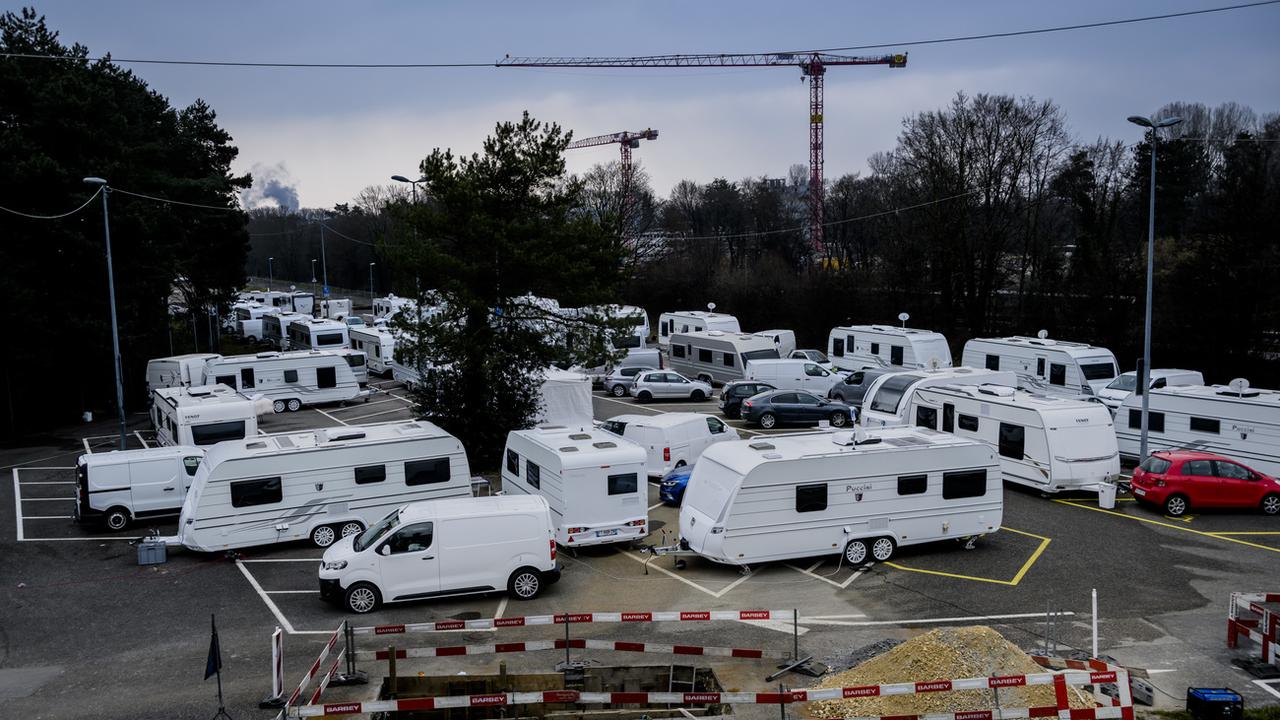 Des gens du voyage avec des caravanes en provenance de France stationnent sur le parking de la Bourdonnette, le samedi 4 mars 2023. [Keystone - Jean-Christophe Bott]
