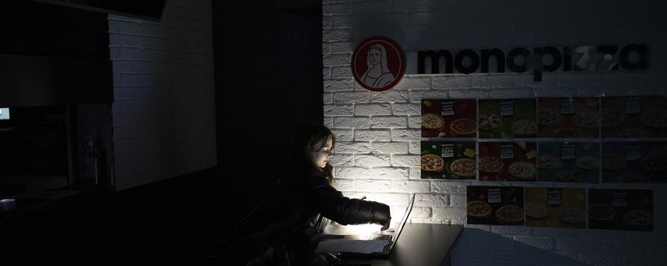 Une serveuse dans un restaurant ukrainien durant une coupure d'électricité. [Keystone/AP - Daniel Cole]