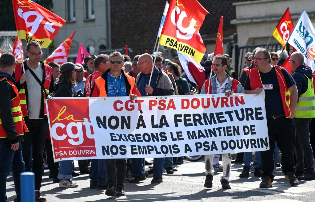 Des syndicalistes de la CGT du site local de Stellantis protestent contre la fermeture de l'usine du Groupe PSA à Douvrin, lors de l'inauguration de l'usine Automotive Cells Company (ACC). [AFP - Denis Charlet]