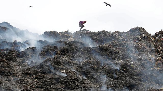 Une personne récolte des matériaux recyclables sur une décharge fumante à Calcutta. Inde, le 22 avril 2018. [Reuters - Rupak De Chowdhuri]