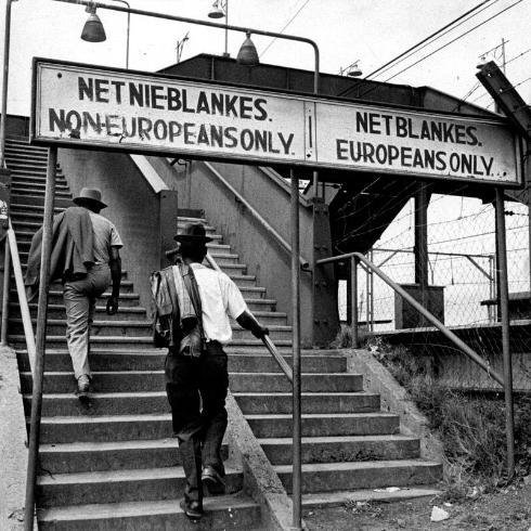 Panneaux dans une gare sud-africaine à l'époque de l'apartheid. L'escalier de gauche est destiné aux non-Européens alors que celui de droite est réservé aux Européens. [Ernest Cole]