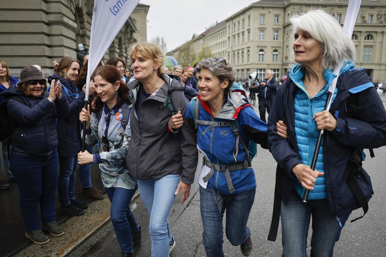 Irene Wettstein, Valérie D'Acremont, Bastienne Joerchel, et Julia Steinberger, initiatrices de "La Marche Bleue", de droite à gauche, sont applaudies par les manifestants du Palais fédéral le samedi 22 avril 2023 à Berne. [Keystone - Peter Klaunzer]