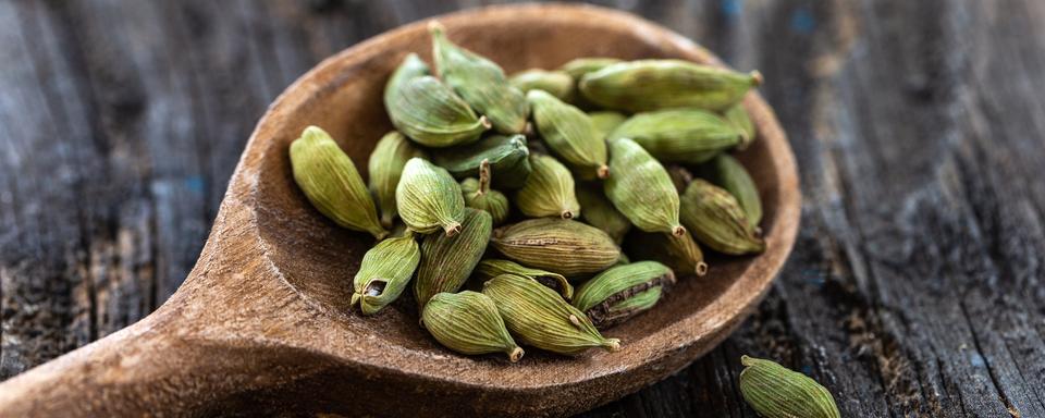 Une cuillère en bois remplie de cardamome. [Depositphotos - Jpcsprod]