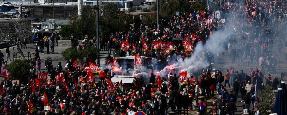 Des manifestants brandissent des fusées éclairantes et des drapeaux syndicaux à Marseille lors de la 10e journée de mobilisation conte la réforme des retraites en France, le 28 mars 2023. [AFP - Christophe Simon]