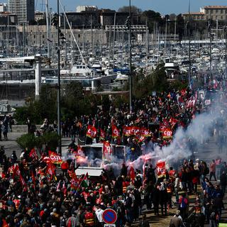 Des manifestants brandissent des fusées éclairantes et des drapeaux syndicaux à Marseille lors de la 10e journée de mobilisation conte la réforme des retraites en France, le 28 mars 2023. [AFP - Christophe Simon]