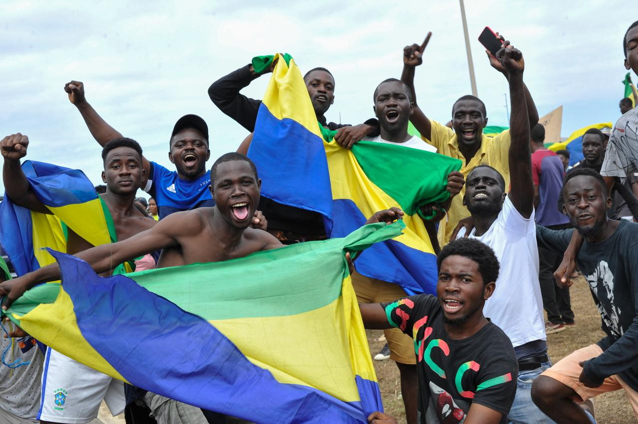 Des hommes agitent des drapeaux gabonais pour célébrer le coup d'Etat, le mercredi 30 août 2023 à Akanda, sur la côte nord-ouest. [Kestone - EPA/STR]