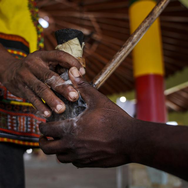 Les Ras Wilkins et Richie s'échangent une pipe de chalice dans laquelle les membres du mouvement rastafari fument de la marijuana sacrée, le 14 mai 2023. [Keystone/AP Photo - Jessie Wardarski]
